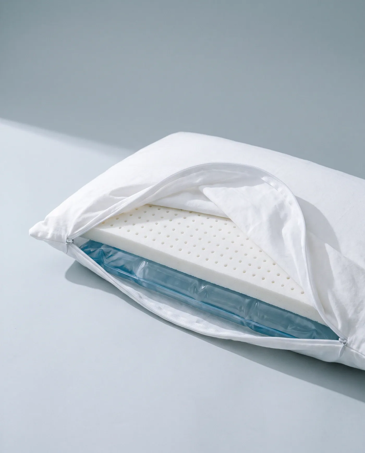 Cutaway of a Mediflow water pillow showing the white comfort layer resting on a blue water pouch