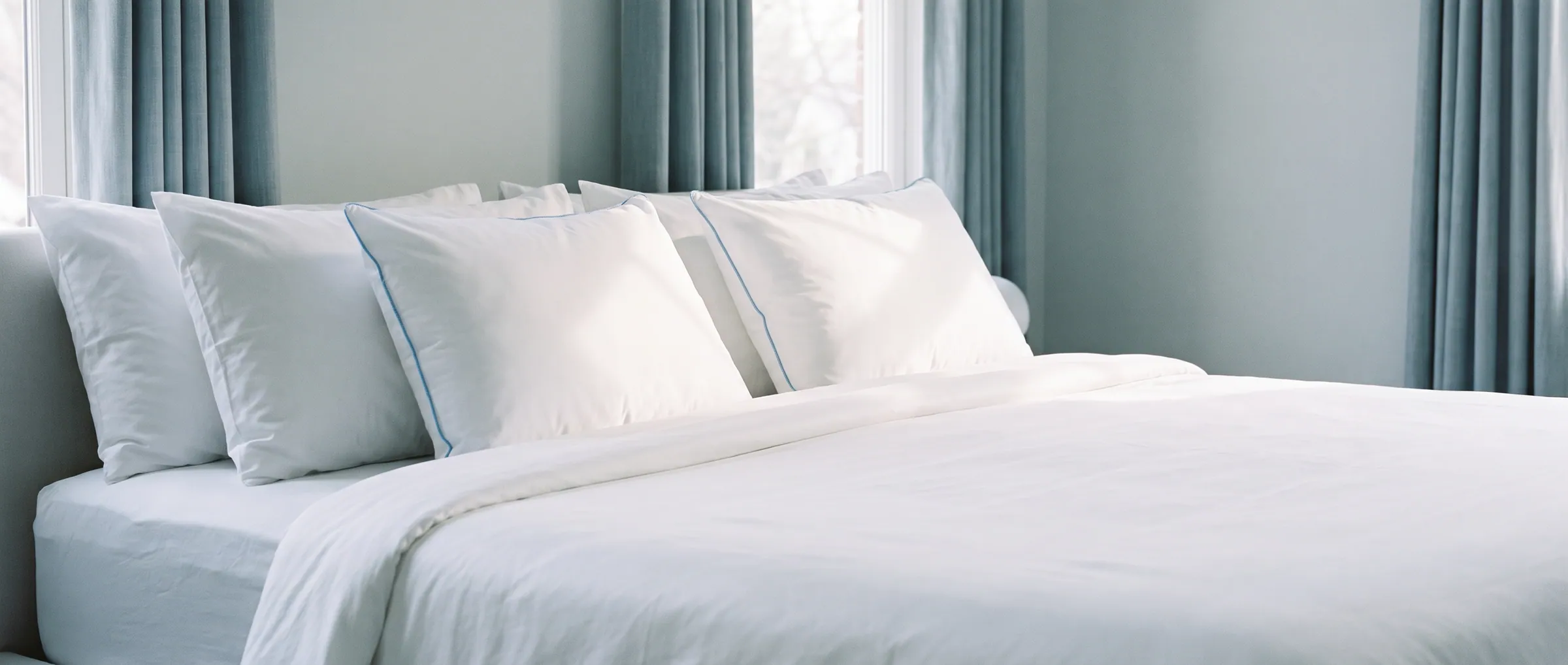 A row of white Mediflow water pillows lined up on a neatly made bed