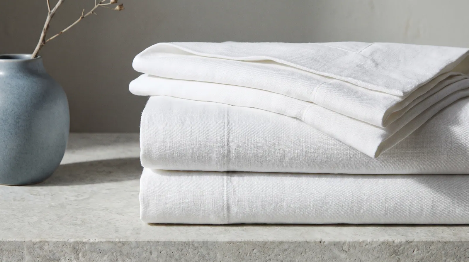 Folded white cotton pillowcases stacked neatly in soft side light