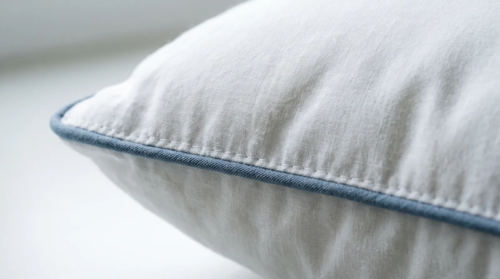 Macro photograph of the stitched corded edge of a white cotton pillow